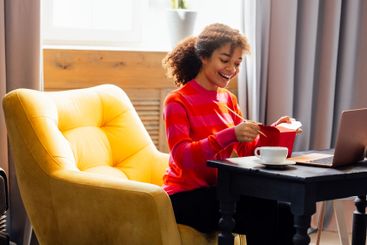 Cute African woman in sweater is sitting in yellow chair...