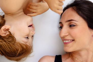 A close-up portrait in profile of a laughing mother and...
