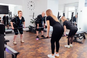 Elderly man performs exercise with barbell under...