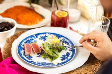 A close-up of a plate with blue decor and pieces of fish...