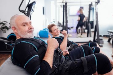 Elderly couple sits on massage chairs while waiting for...