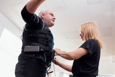 Female coach puts on suit for ems workout on greyhaired...