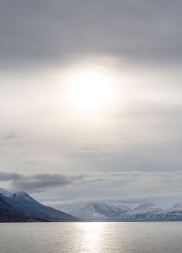Sunset over snowy mountains and sea in Svalbard, Norway