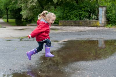 Cute little girl jumping over a puddle