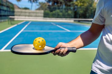 Close-up of a male hand holding a pickleball paddle and...