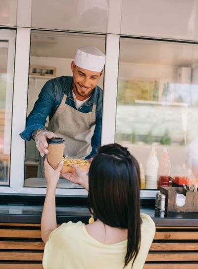 smiling young chef giving french fries and coffee to go...