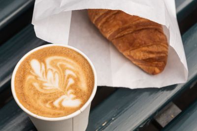 Cappuccino coffee in a paper cup , and croissant, on...