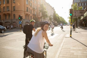 Young man and woman riding bicycles on city street