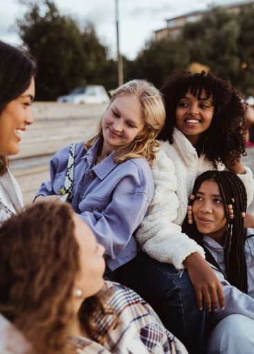Smiling female friends talking with each other while...