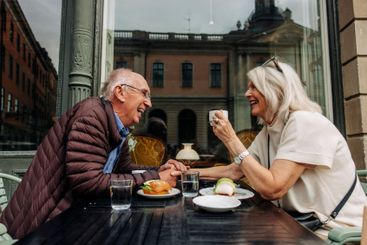 Happy senior man holding hand of woman while sitting...
