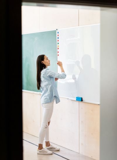 thoughtful asian student girl writing on whiteboard...