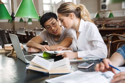 Happy student couple studying at the library