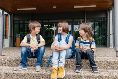 Children sit on the steps of the school and talk....