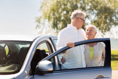 happy senior couple with car in summer