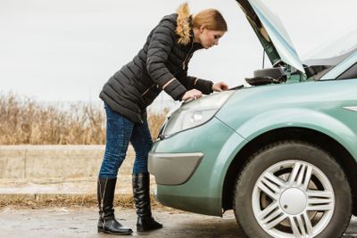Blonde woman and broken down car on road