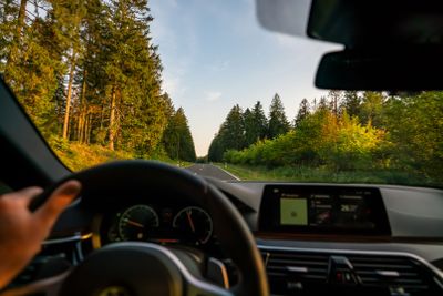 hands of car driver on steering wheel, road trip,...