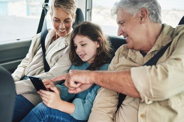 Child, grandparents and phone on road trip in car...