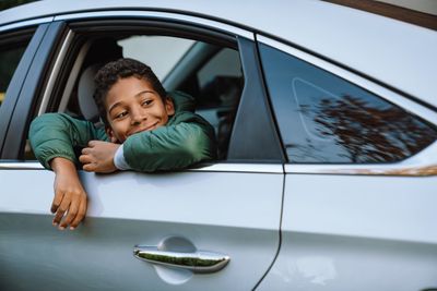 Black boy smiling and looking aside while sitting in car