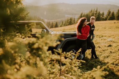 Young couple relaxing by a terrain vehicle hood at...