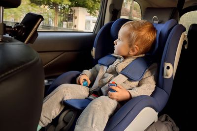 Little toddler boy riding in car and looking out of the...