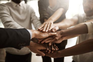 Businesspeople with their hands together in a huddle...