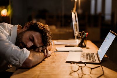 White bearded man sleeping while working with laptop in...