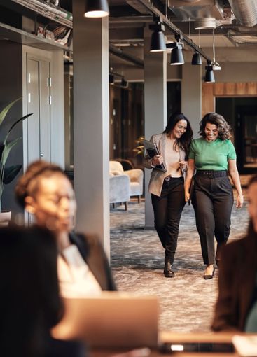 Happy female entrepreneurs walking and talking in office