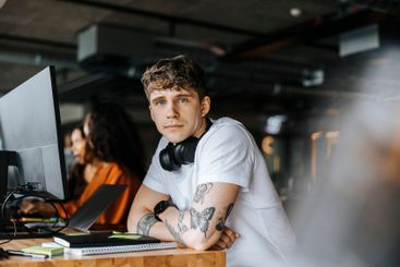 Portrait of young male entrepreneur leaning on elbows at...