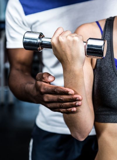 Cropped image of male trainer assisting fit woman 
