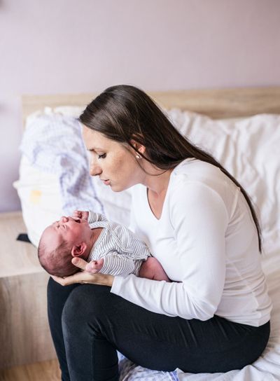 Beautiful young mother with her newborn baby son, bedroom