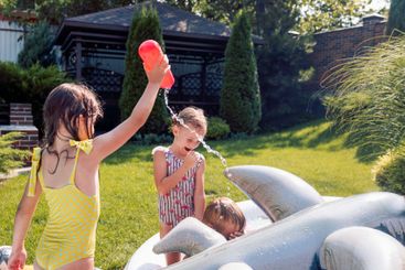 Small children splash water and have fun in the backyard...