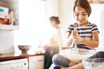 Messy, happy and child baking in the kitchen with parent...