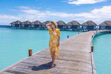 A young woman in a dress stands on a wooden bridge near...